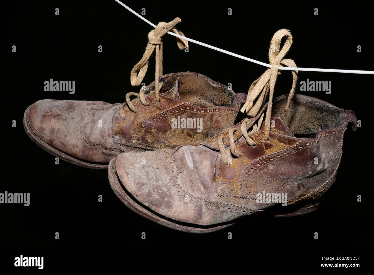 Ammuffito stivali vecchi appesi su una linea. È arrivato il momento di appendere gli scarponi. Foto Stock