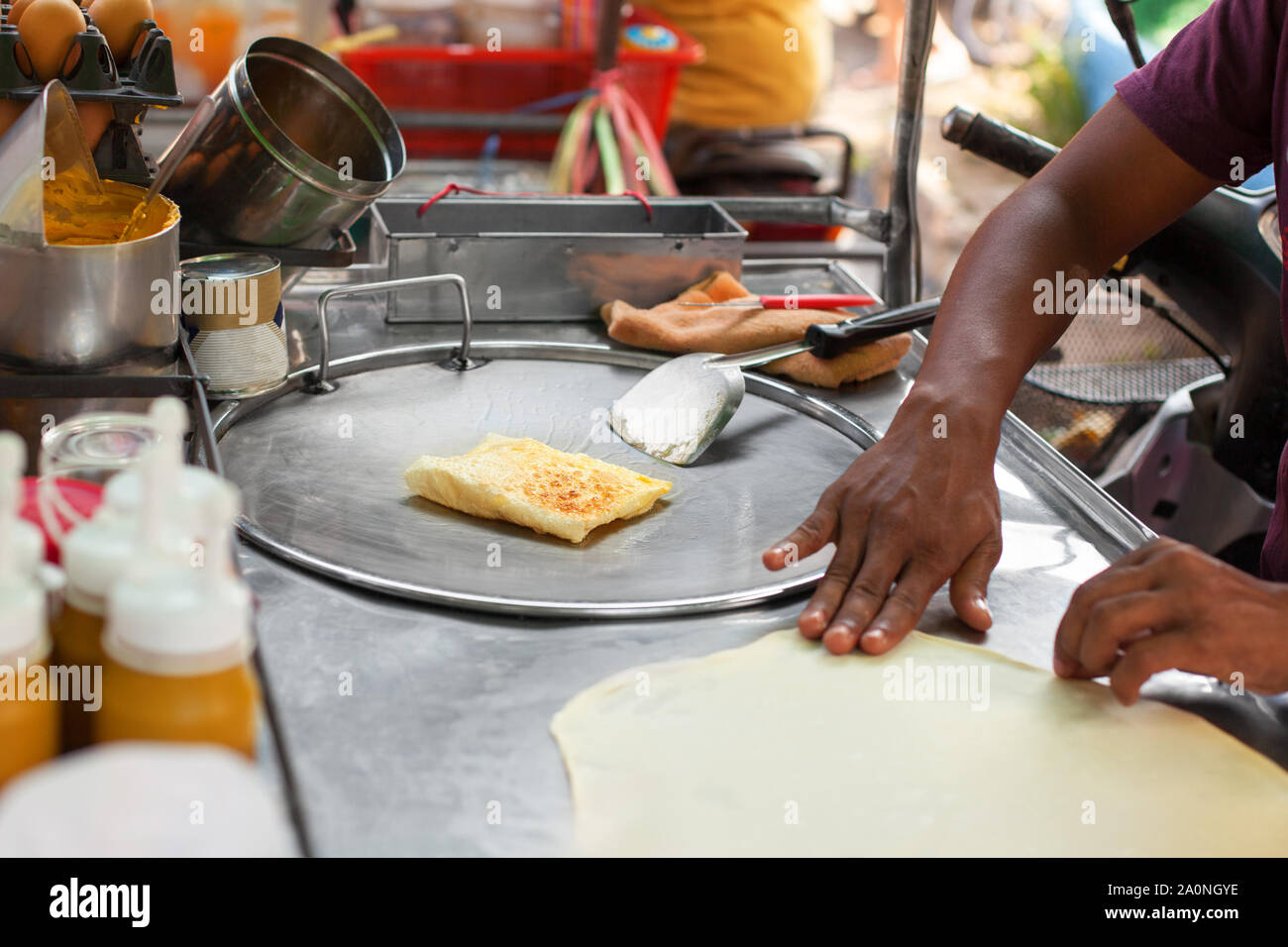 La cucina Tailandese tradizionale di banane fritte frittelle roti closeup, asian street il cibo preparato in Thailandia, man mano dello chef friggere le frittelle su piastra Foto Stock