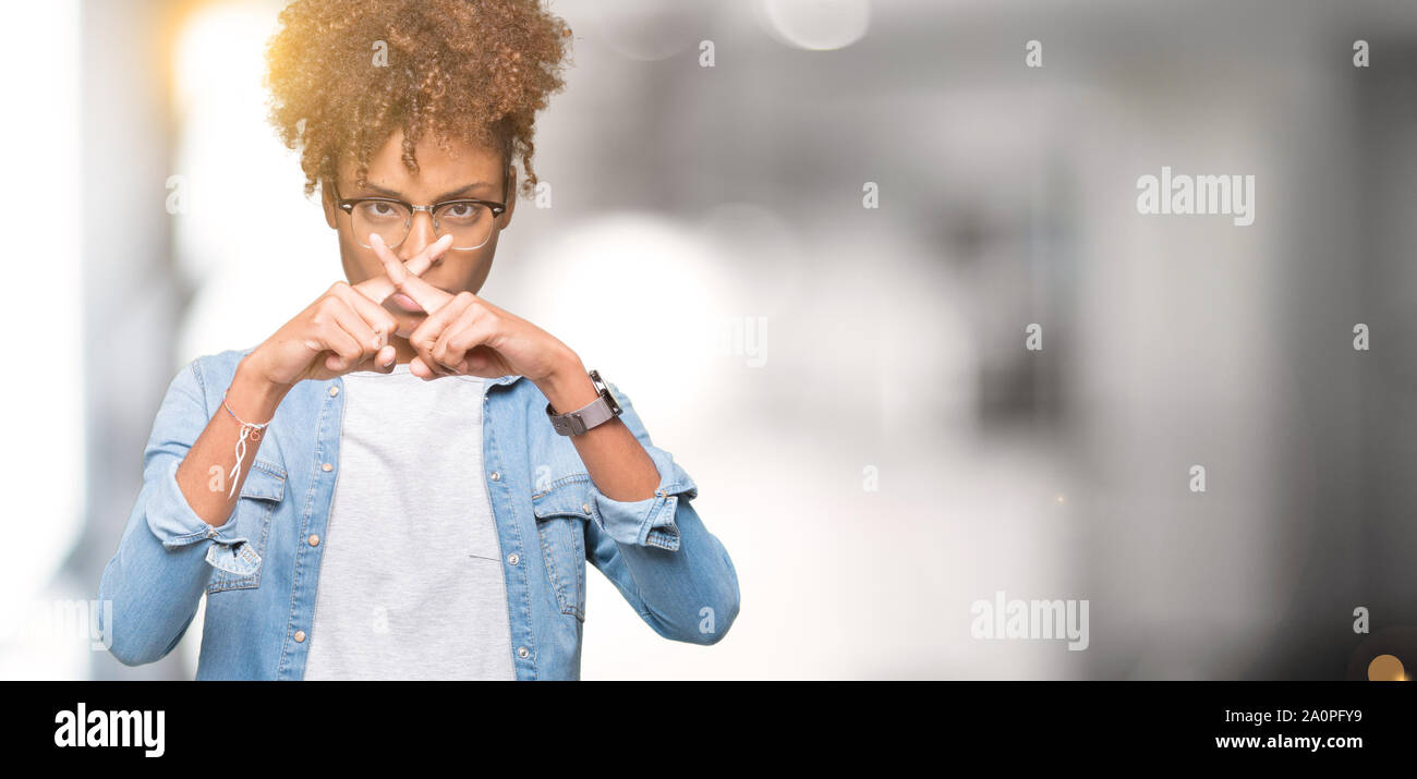 Bella giovane americano africano donna che indossa gli occhiali su sfondo isolato rifiuto espressione dita incrociate facendo segno negativo Foto Stock