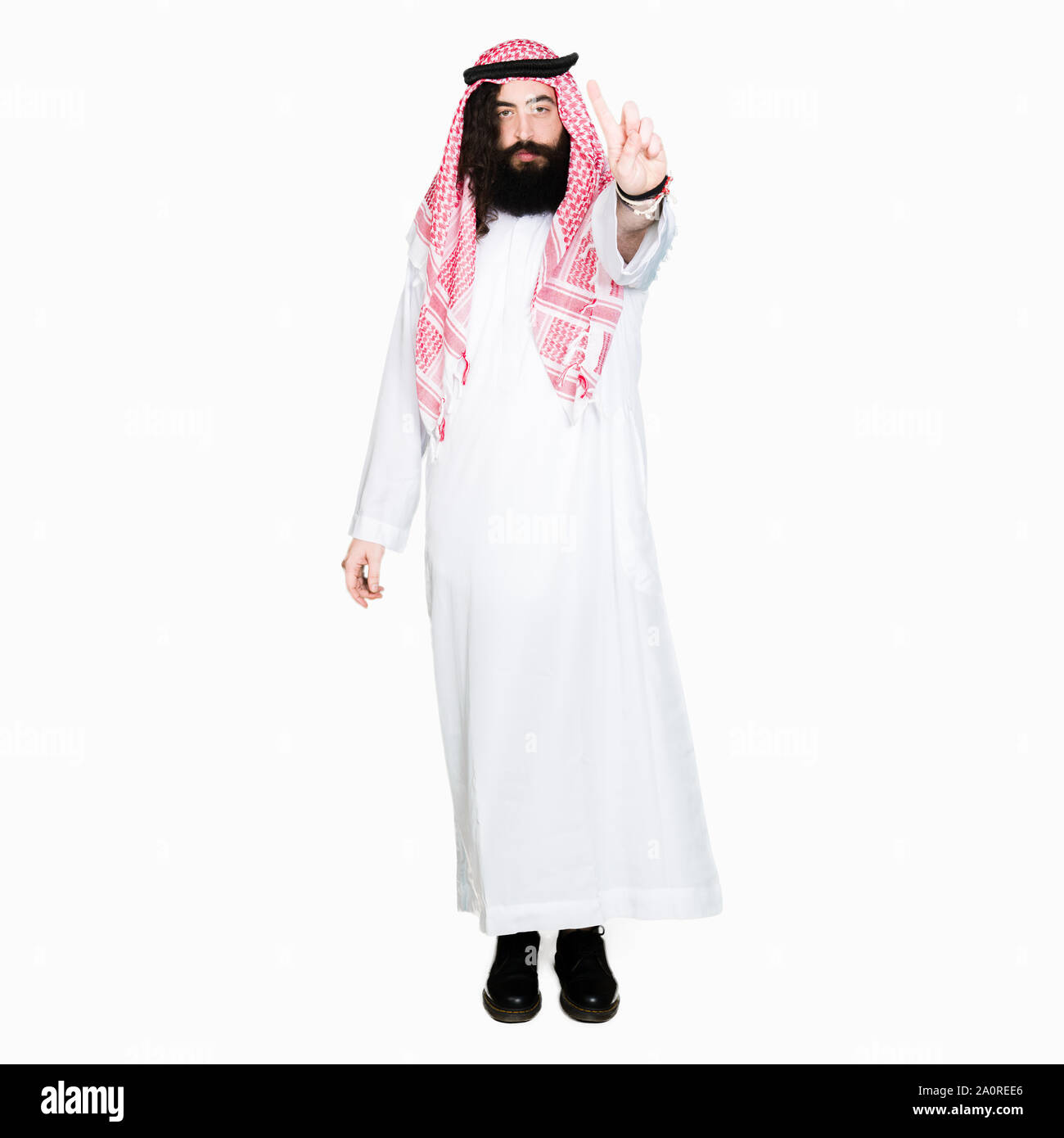 Arabian business man con capelli lunghi indossando il tradizionale keffiyeh sciarpa puntando con il dito in alto e espressione arrabbiato Foto Stock