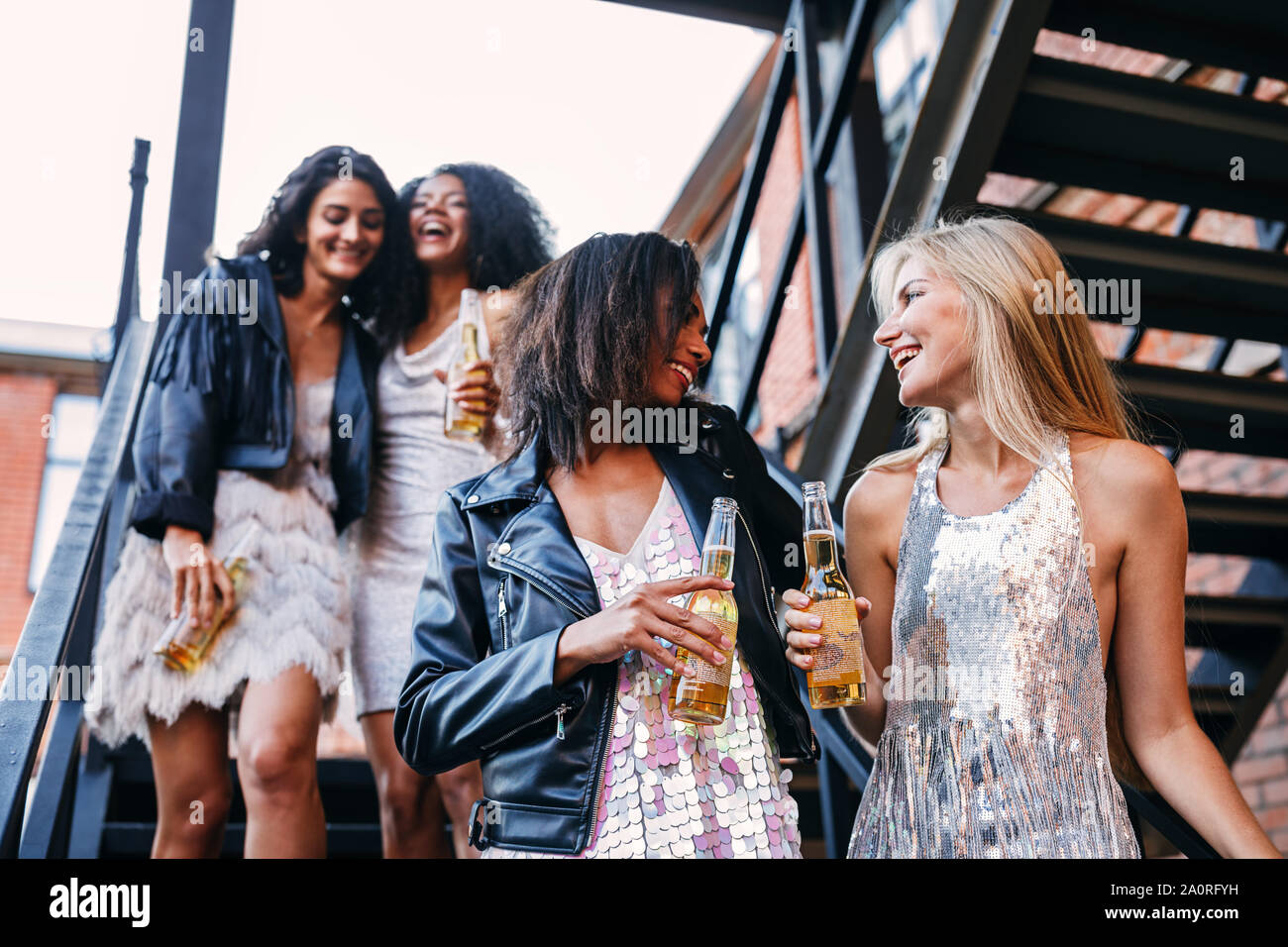 Felici donne camminando con le bottiglie di birra. Giovani amici di sesso femminile avente il divertimento mentre fai un passo giù per le scale. Foto Stock