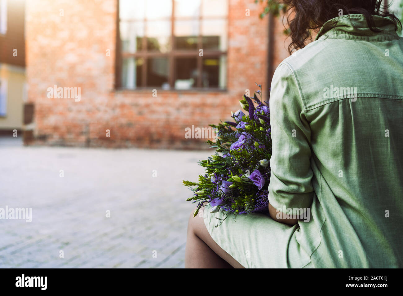 Una donna si siede su una panchina nel cortile in un menta-colorato abito di lino Foto Stock