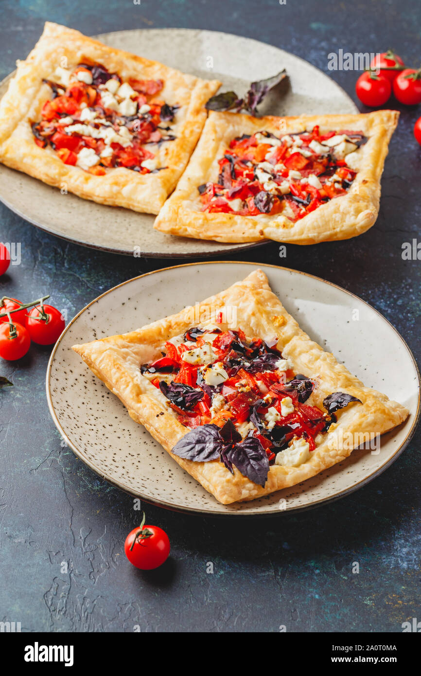 Pasta sfoglia canapes con pomodori, dolci peperoni, salame, formaggio feta e basilico viola. Foto Stock