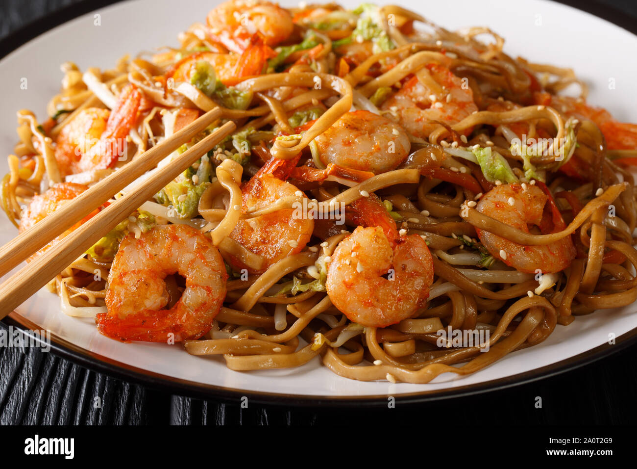 Gustosa Chow Mein tagliatelle con gamberetti, le verdure e i semi di sesamo close-up su una piastra sul tavolo orizzontale. Foto Stock