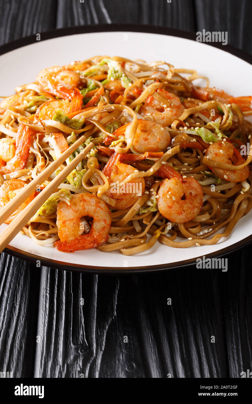 Servire di Chow Mein tagliatelle con gamberi e verdure close-up su una piastra sul piano verticale. Foto Stock