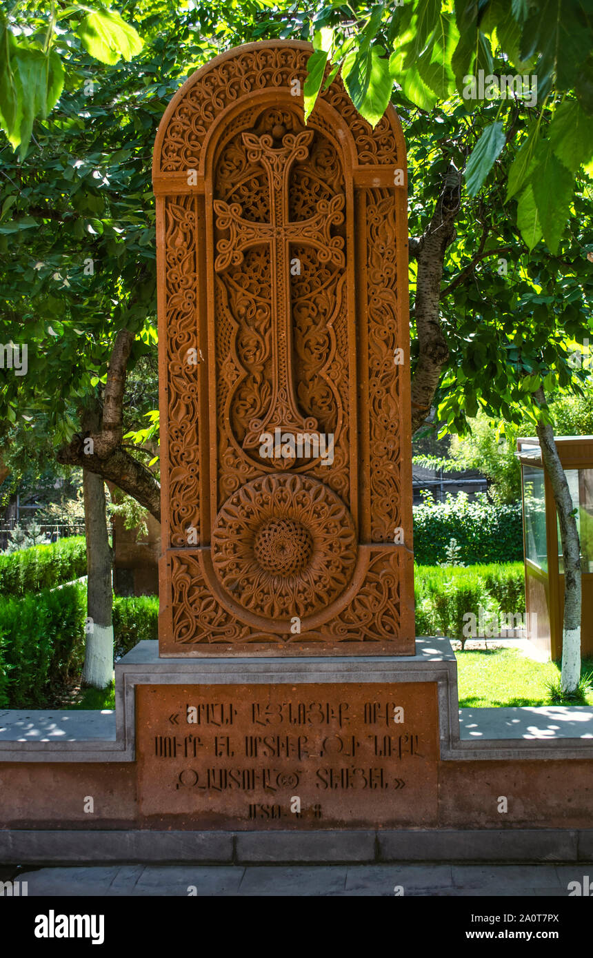 Khachkar in pietra di tufo rosso con un arco ovale oltre la croce e openwork ornamento in un cerchio nel cortile del ''Zoravor " Tempio di Yerevan Foto Stock