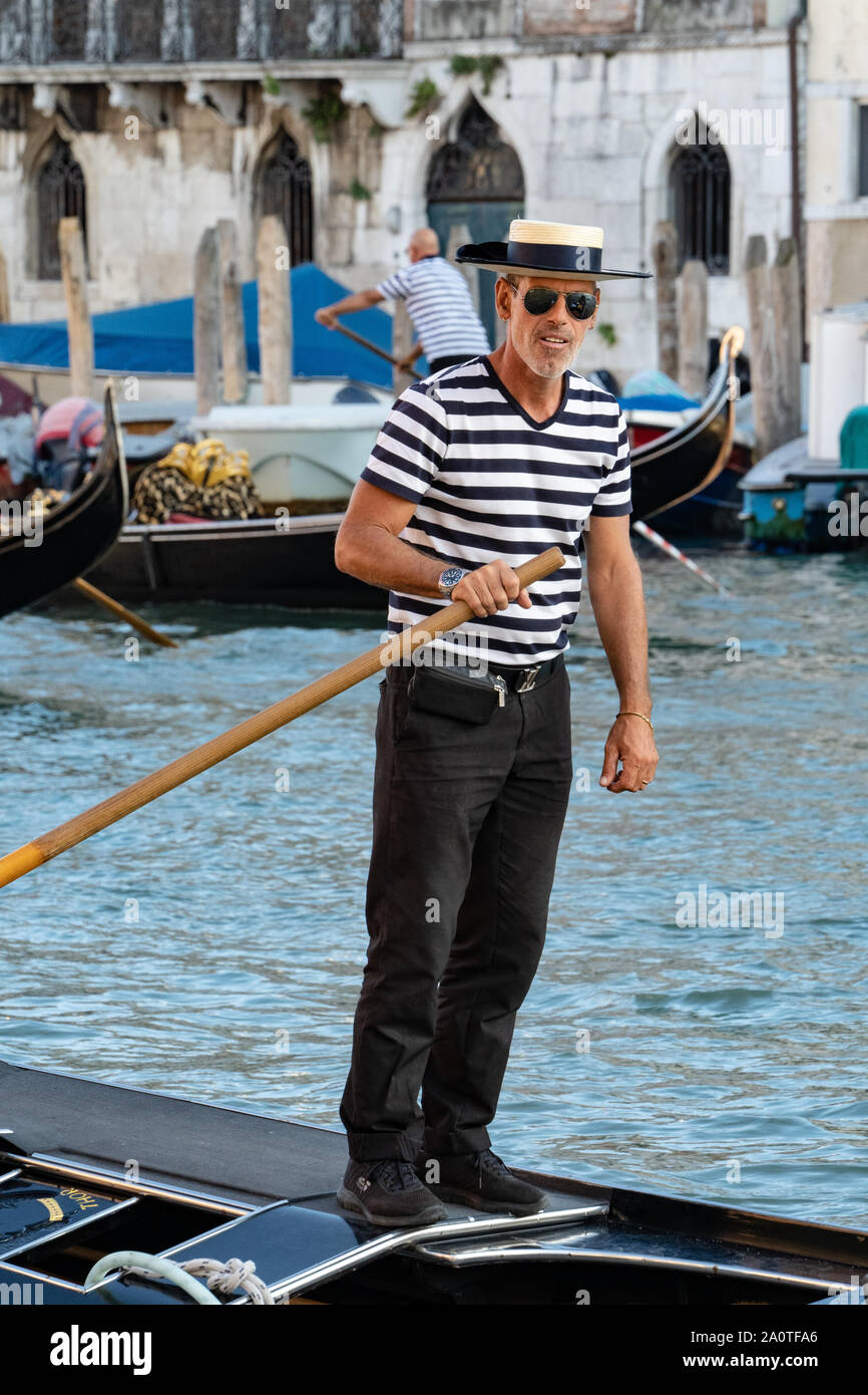 Un gondoliere in tradizionale camicia a righe e paglia navigante hat su una  gondola su canali di Venezia, Italia Foto stock - Alamy
