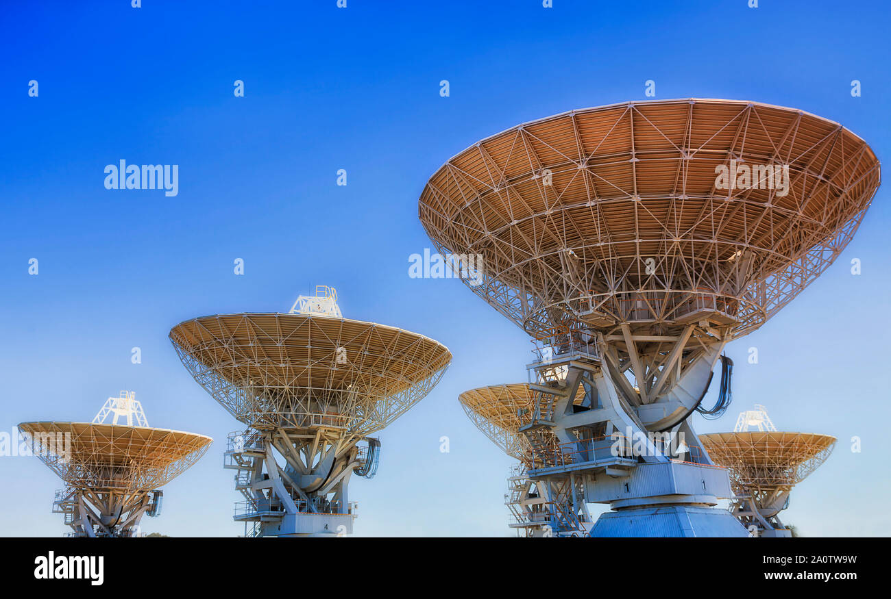 Cinque antenne radio come parte di profonda esplorazione spaziale array in remoto outback australiano città Coonabarabran Namoi Street contro il cielo blu e chiaro. Foto Stock