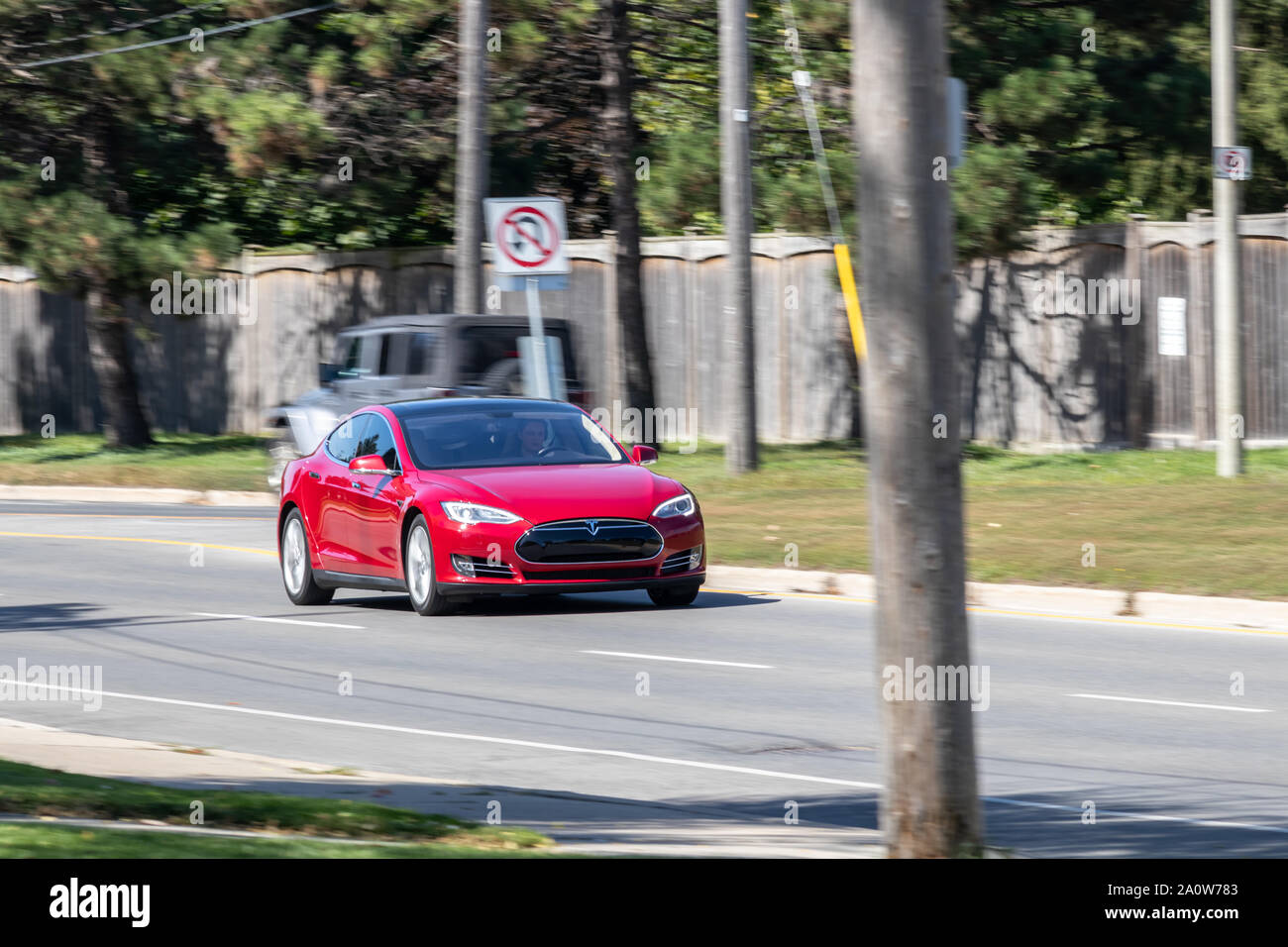 Rosso Modello Tesla S guidando su strada in una giornata di sole. Foto Stock