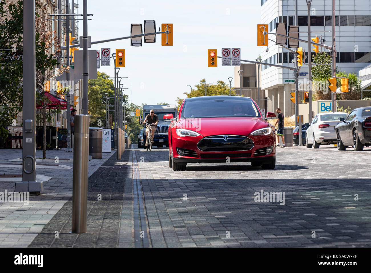 Il veicolo elettrico, rosso Tesla Model S la guida attraverso una zona urbana in London, Ontario. Foto Stock