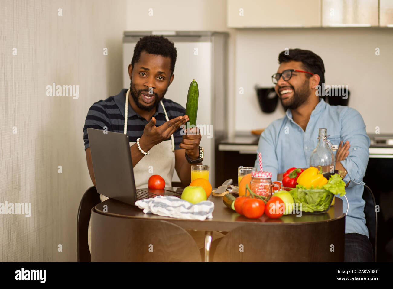 Bello stupiti americano africano giovane puntando con il dito al suo amico indiano che andare a cucinare e sorridente. Gioiosa multi etnico sitti studenti Foto Stock