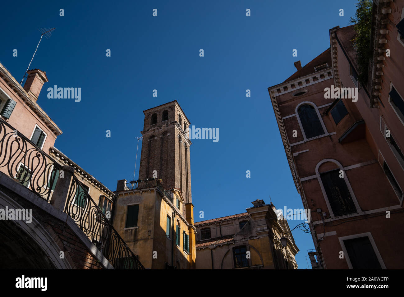 Vista da un canale veneziano, guardando su un ponte e campanile Foto Stock