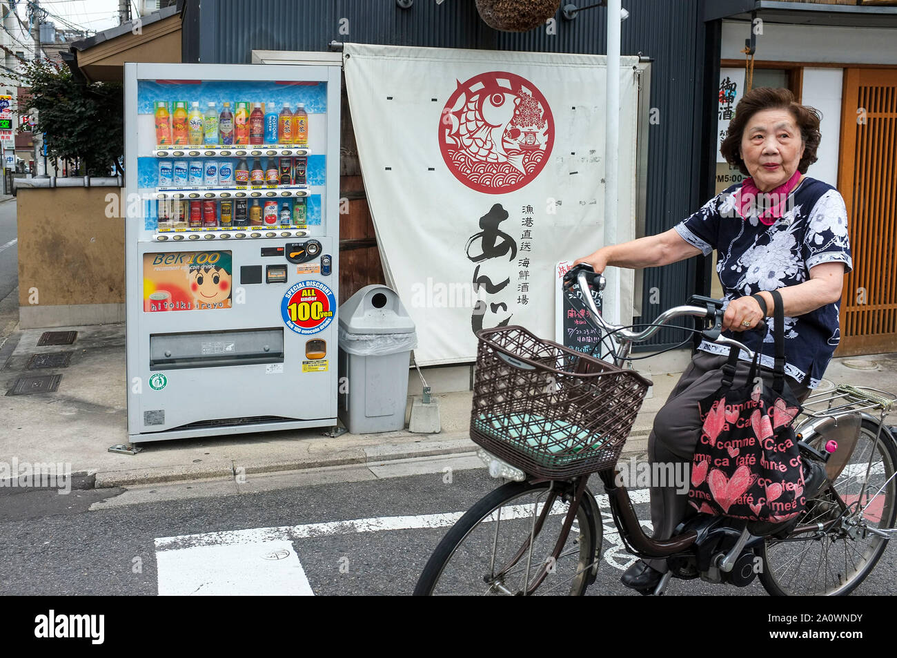 Un senior donna corse in bicicletta in una strada a Kyoto, in Giappone. Foto Stock
