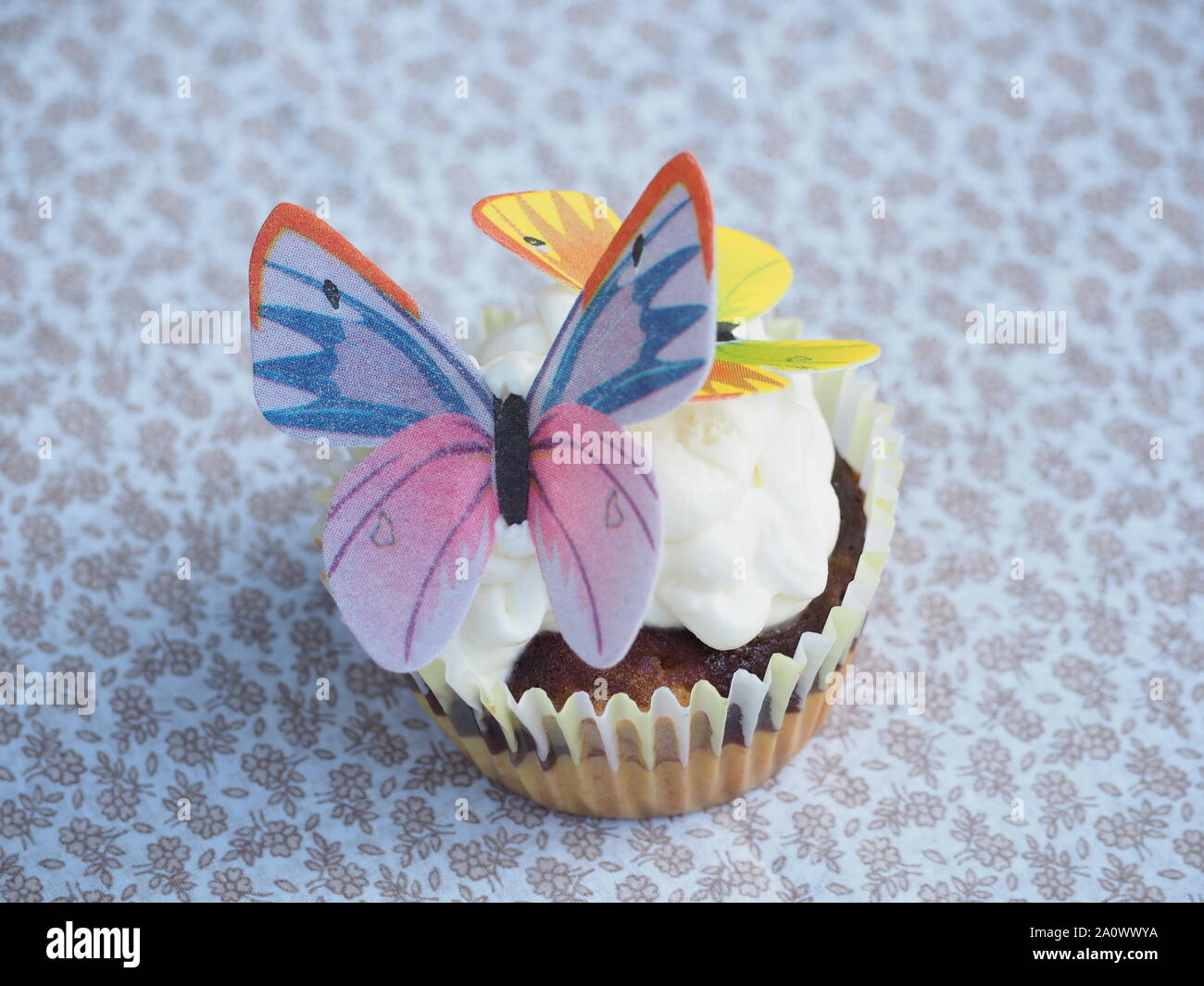 Deliziosa torta di coppa con farfalla su una tovaglia Foto Stock