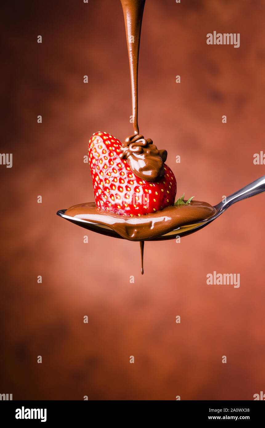 Un cucchiaio di isolati con fragole e cioccolato fondente fuso Foto Stock