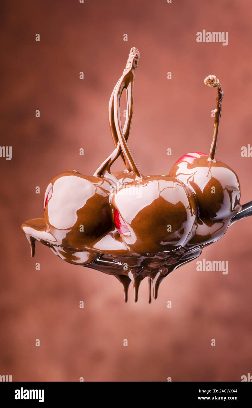 Cucchiaio di succose ciliegie ricoperte con cioccolato fondente fuso Foto Stock