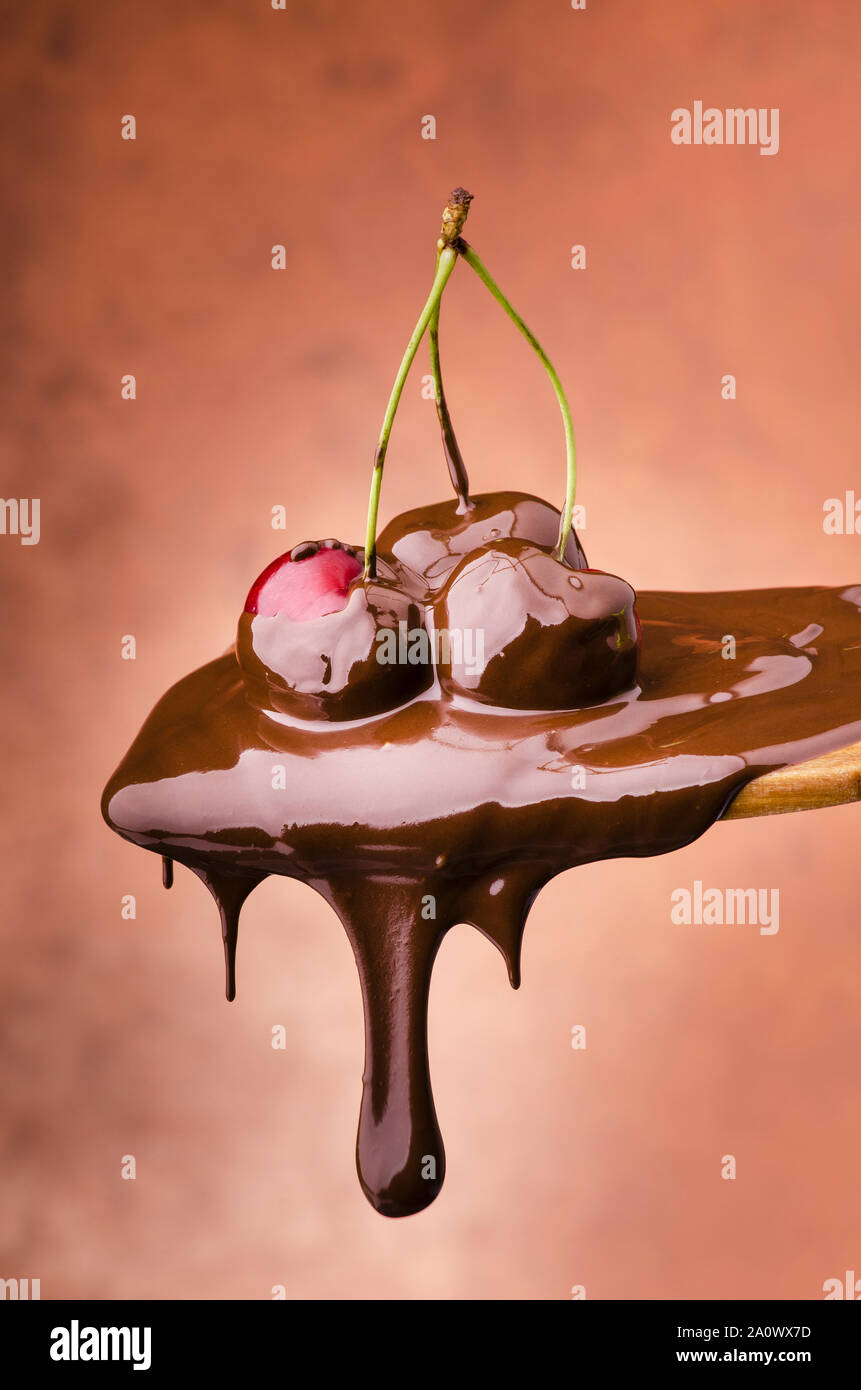 Cucchiaio di succose ciliegie ricoperte con cioccolato fondente fuso Foto Stock