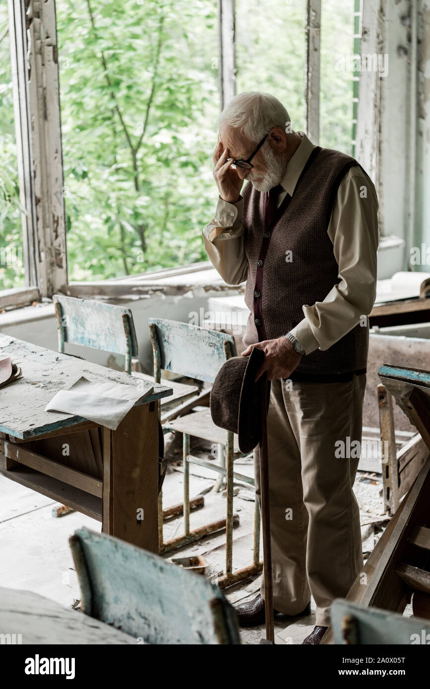 Messa a fuoco selettiva del triste uomo senior holding hat permanente, mentre in classe Foto Stock