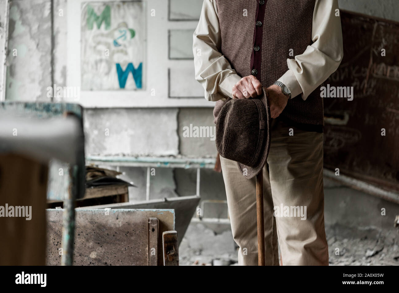 Vista ritagliata della senior man holding hat mentre in piedi con bastone da passeggio Foto Stock