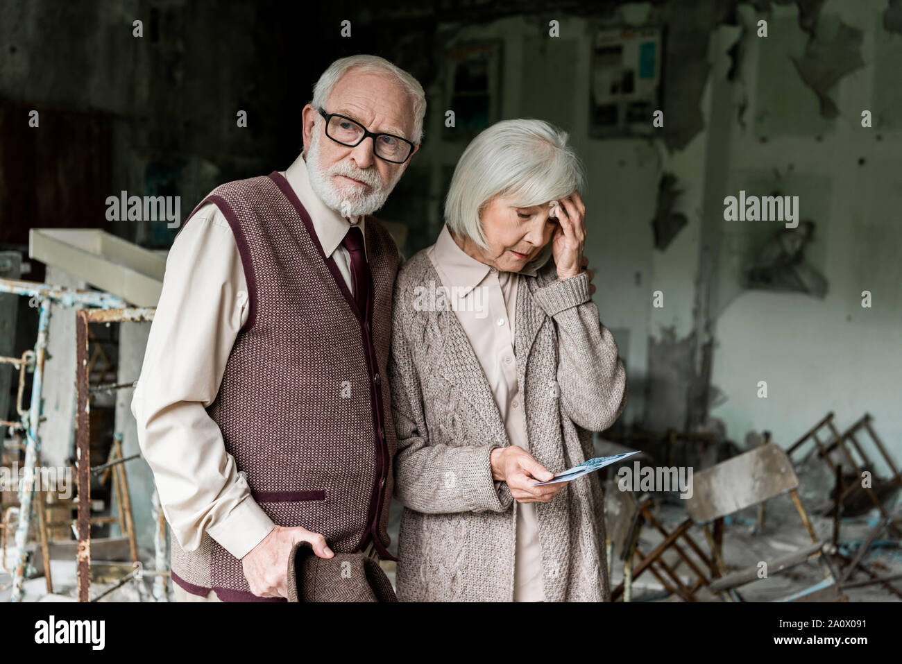 Coppia in pensione in piedi nella scuola abbandonata e foto di contenimento Foto Stock
