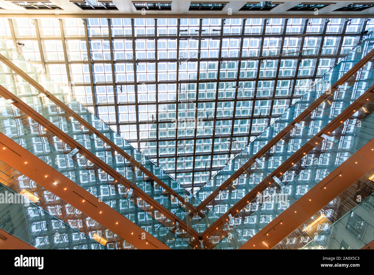 Tokyo, Marunouchi. KITTE building interior. L'atrio triangolare tetto di vetro visualizzati direttamente dal basso, diurno. Arancione marrone e blu ghiaccio colore Foto Stock