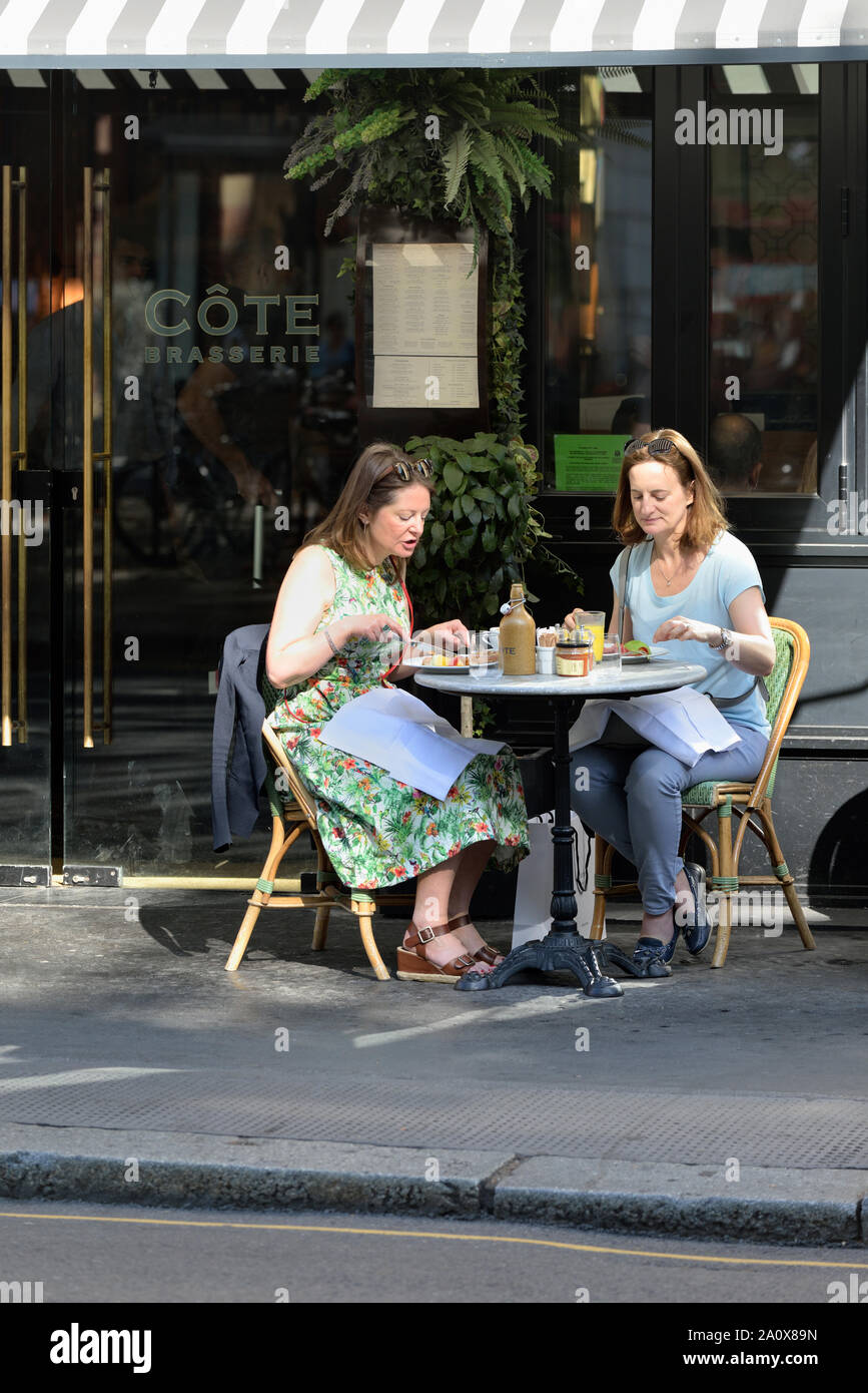 Due signore di consumare la colazione al di fuori di una Cote Brasserie Ristorante, Sloane Square, Kensington e Chelsea, West London, Regno Unito Foto Stock