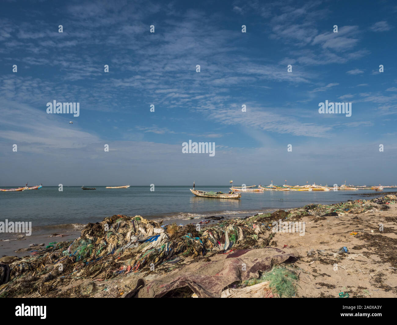 Il Senegal, Africa - 26 Gennaio 2019: un sacco di sacchetti di plastica sulle rive dell'oceano. Concetto di inquinamento. Colorate barche di fisher in background. Il Senegal. Foto Stock