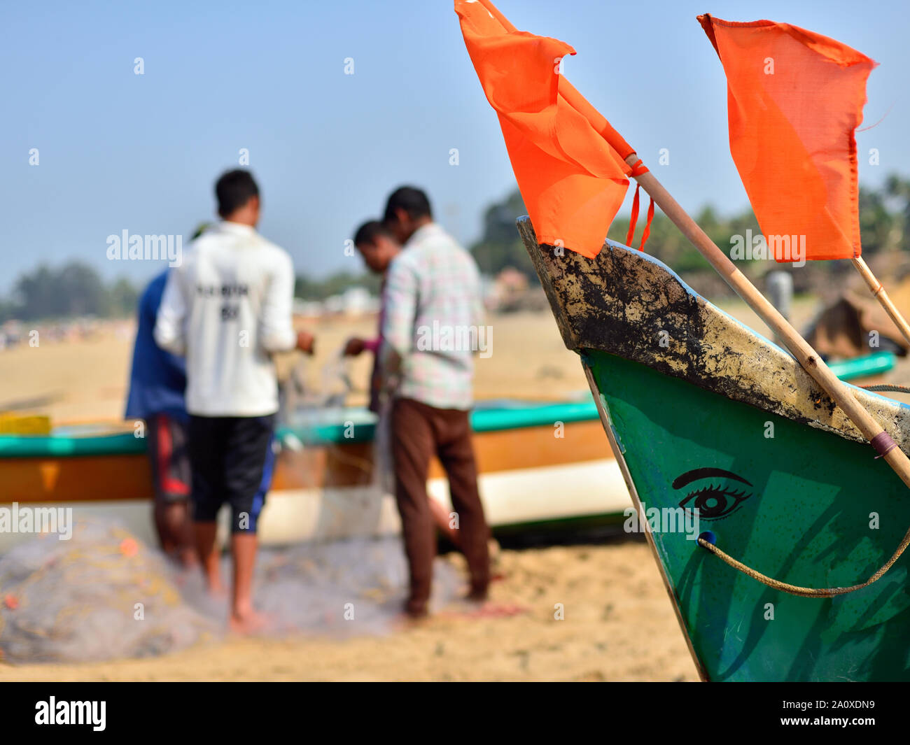 I pescatori sono reti di fissaggio per accanto ai tradizionali barche da pesca sulla spiaggia, Gokarna, India. Foto Stock