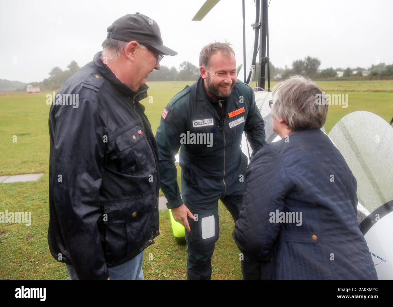 British Adventurer James Ketchell (centro) è accolto da sua madre Trish e padre Giovanni, dopo arrivando a Popham airfield in Hampshire e diventando la prima persona a volare solo il giro del mondo in un pozzetto aperto girocottero. Foto Stock
