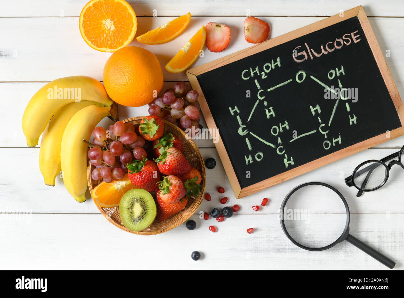 Molecola di glucosio sulla lavagna con un misto di frutta fresca insalata di legno su sfondo bianco, Dieta e scienze alimentari concetto Foto Stock