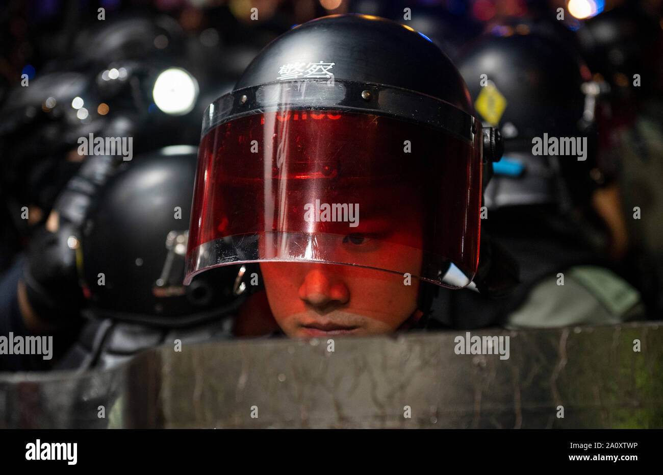 Un riot police officer guarda stando in guardia durante la protesta.Un altro weekend, manifestanti impostare barricata sul fuoco, bruciato una bandiera cinese e la polizia ha sparato spruzzo di pepe in una rinnovata scontri per le lagnanze da parte del governo anti-manifestanti. Foto Stock