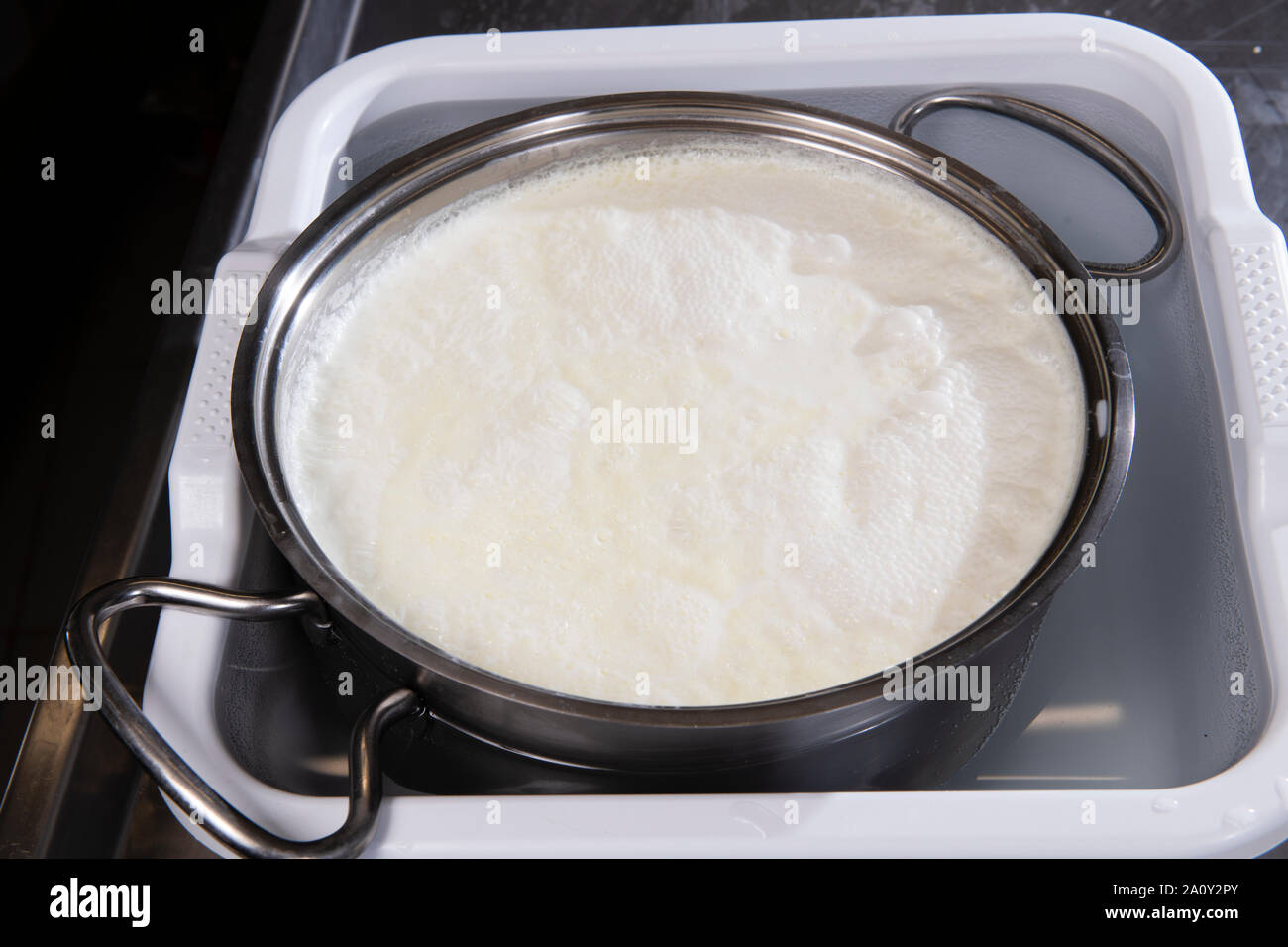 Latte cagliato in una pentola inserita in una ciotola con acqua fresca per  raffreddare Foto stock - Alamy