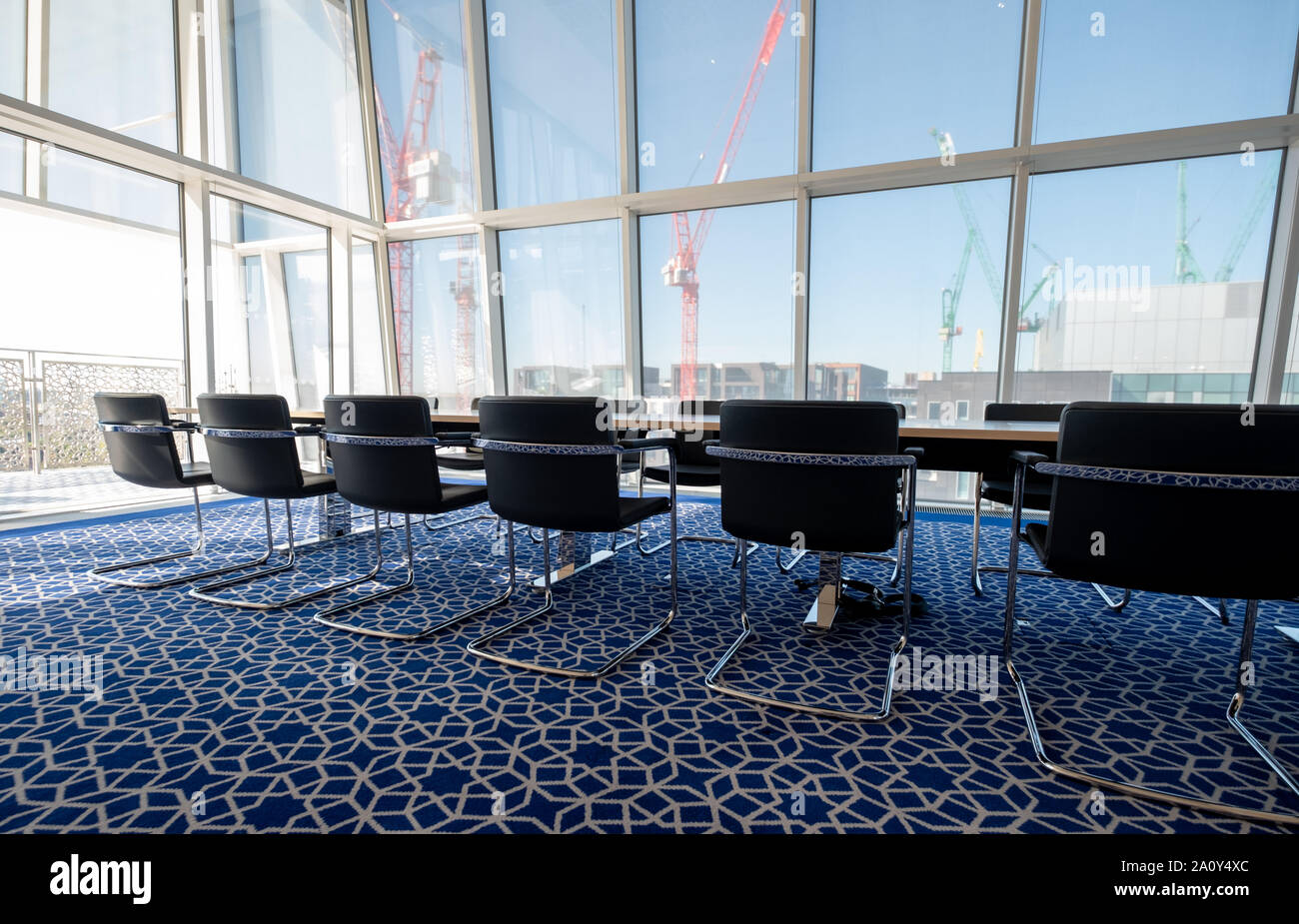 Luce, sunny boardroom con tubolare piegato sedie in acciaio e tappeti blu con disegno geometrico, all'Aga Khan Centro, Kings Cross, London, Regno Unito. Foto Stock