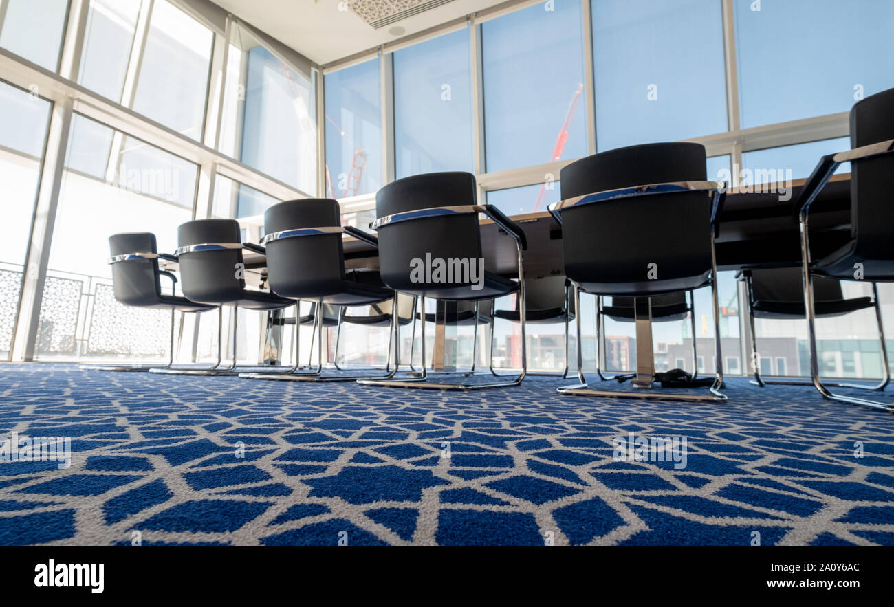 Luce, sunny boardroom con tubolare piegato sedie in acciaio e tappeti blu con disegno geometrico, all'Aga Khan Centro, Kings Cross, London, Regno Unito. Foto Stock