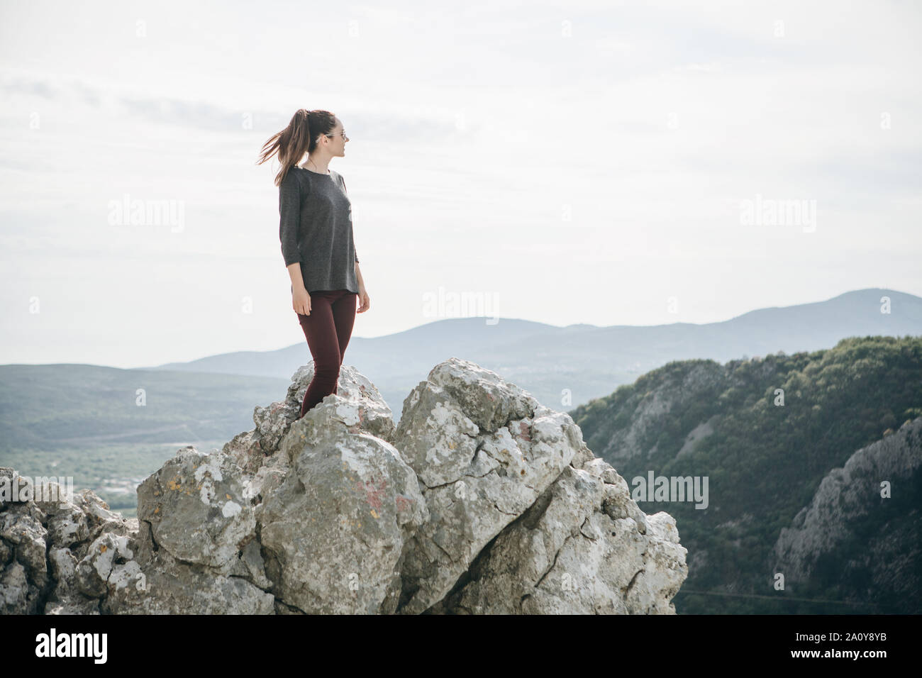 Una ragazza in solitudine si erge sulla cima di una montagna e lei