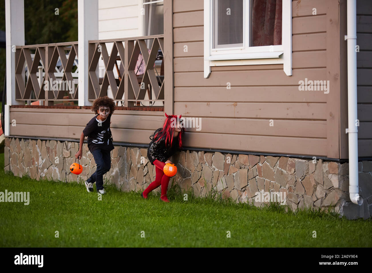 Due bambini furtivo nascondere al di fuori di casa mentre il trucco o il trattamento di Halloween, spazio di copia Foto Stock