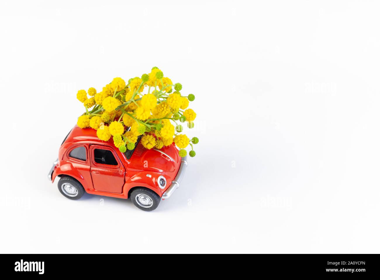 Mosca, Russia - 23 Febbraio 2019: 8 Marzo Giornata Internazionale della Donna con scheda Modello giocattolo auto retrò consegna bouquet di fiori di mimosa sul retro bianco Foto Stock