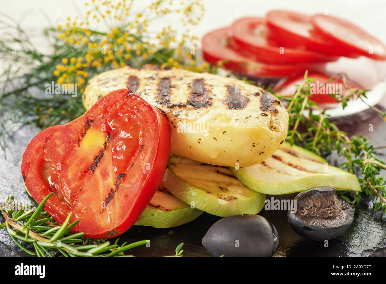 Un pezzo di grigliate il formaggio halloumi con pomodori fritti, zucchine e basilico. Servizio tradizionale del formaggio halloumi. Azienda prodotto naturale. Foto Stock