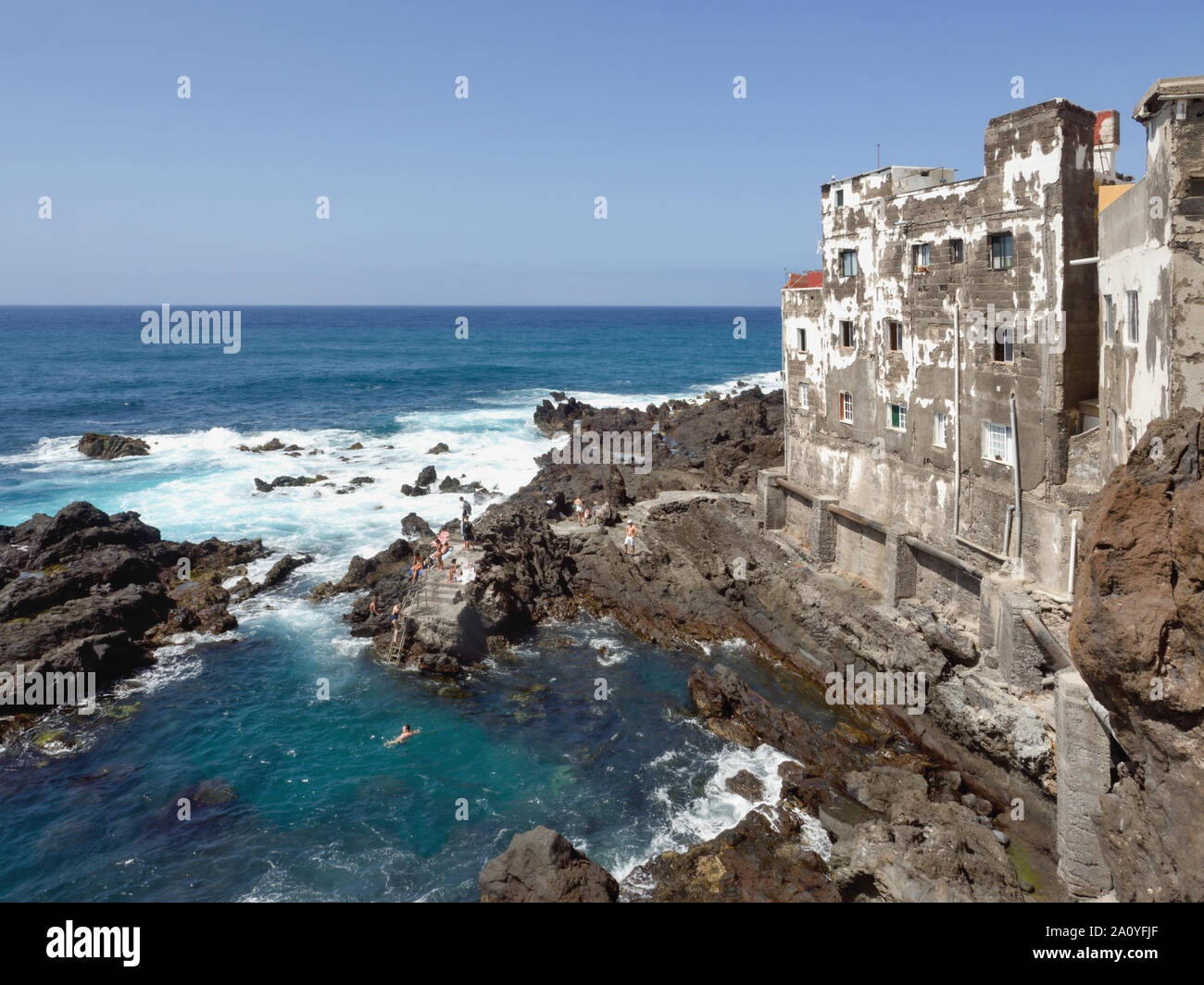 L'Atlantico a Tenerife nel nord sulla Punta Brava. Sulle rocce laviche, quasi in acqua, sono case con sale consumato facciate esterne. Blue sky. Foto Stock