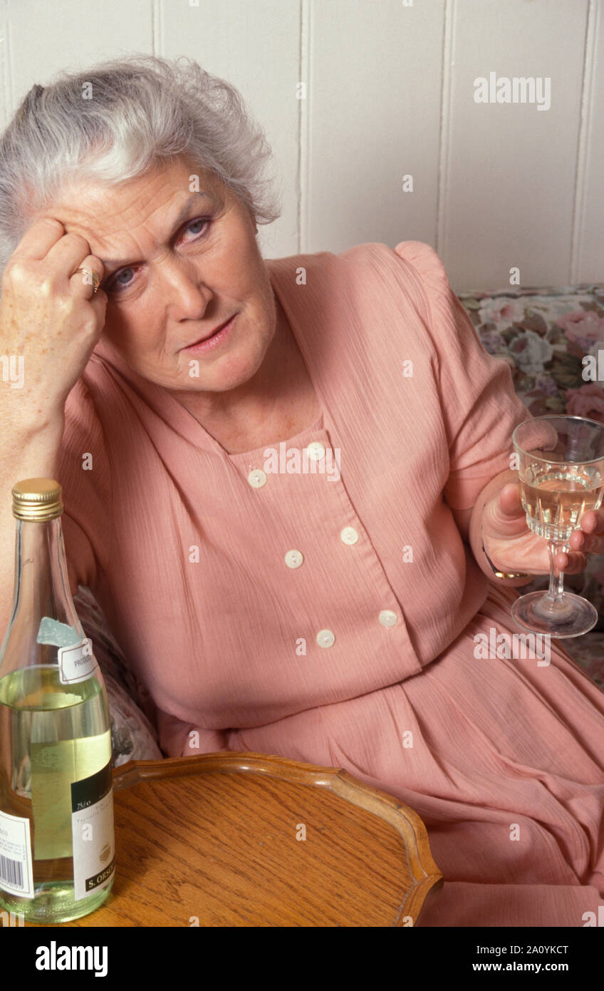 Infelice donna anziana bere il vino Foto Stock