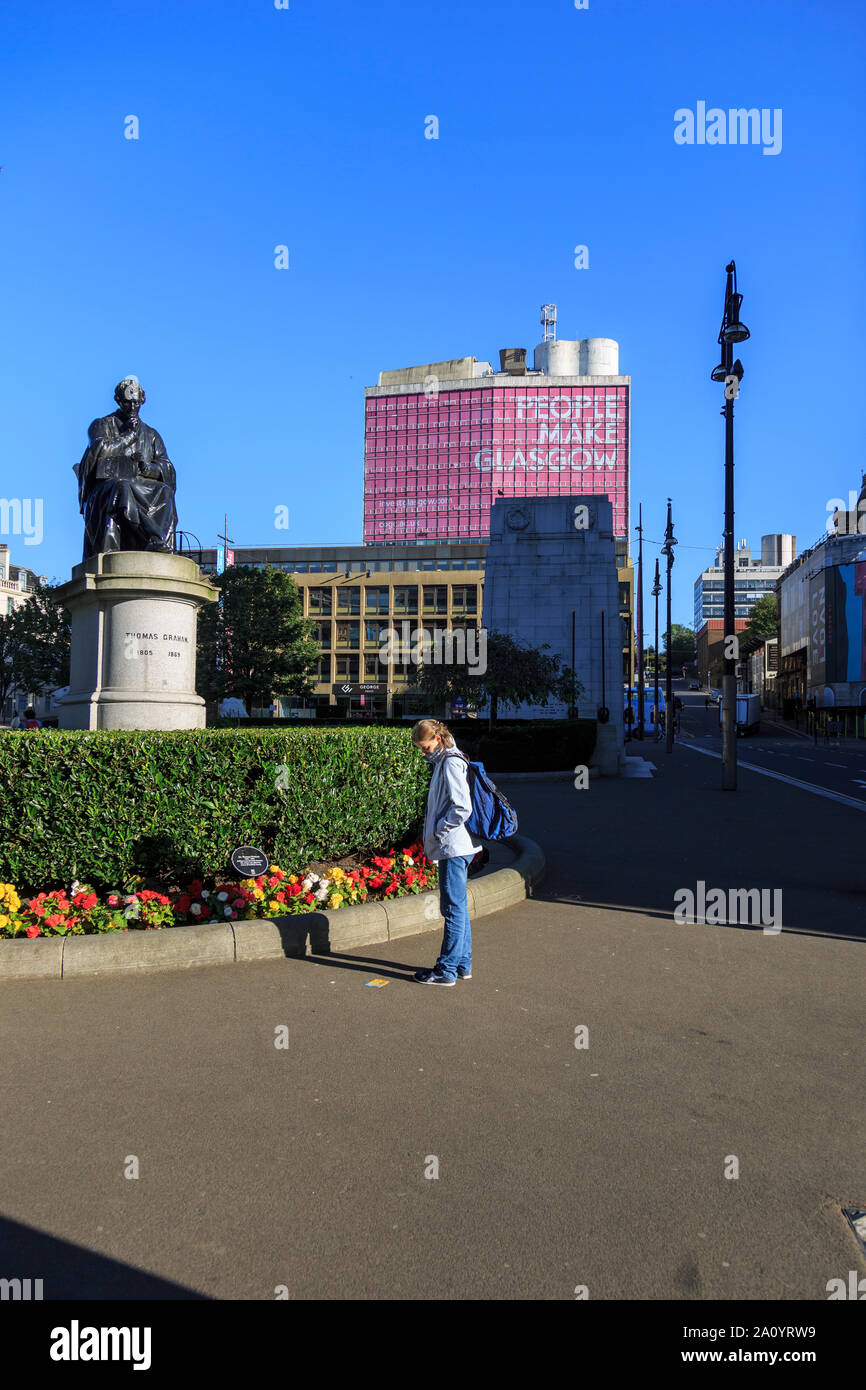 Un visitatore si ferma a meditare una nota sul terreno in George Square, Glasgow. Foto Stock