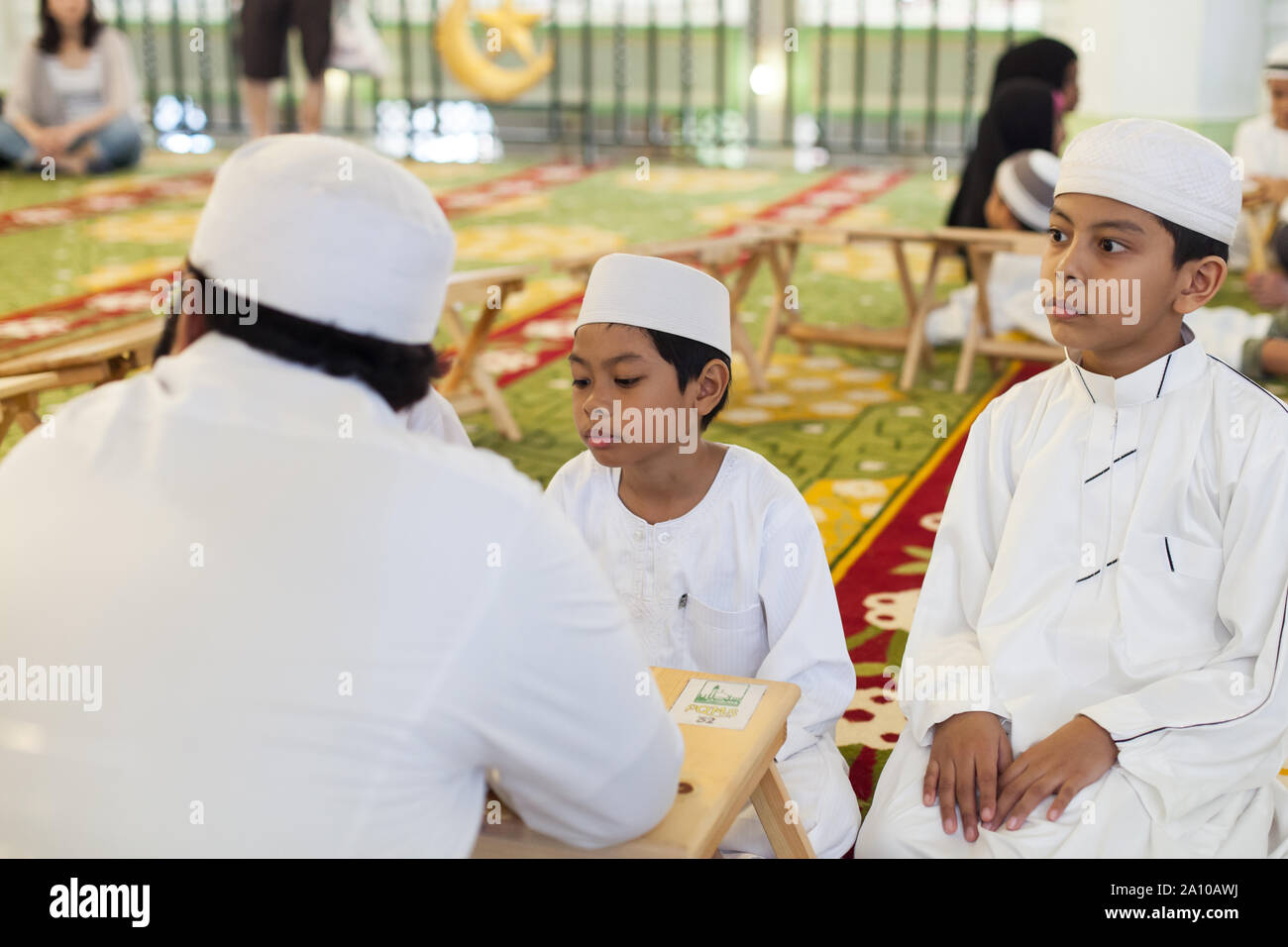 Bambini Malay apprendimento del linguaggio all'interno di Masjid Moschea del Sultano, Singapore Foto Stock