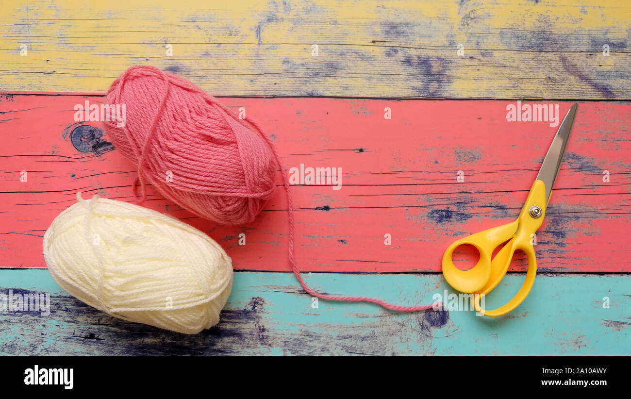 Rosa e Bianche palline di filato con un paio di forbici su sfondo colorato. Foto Stock