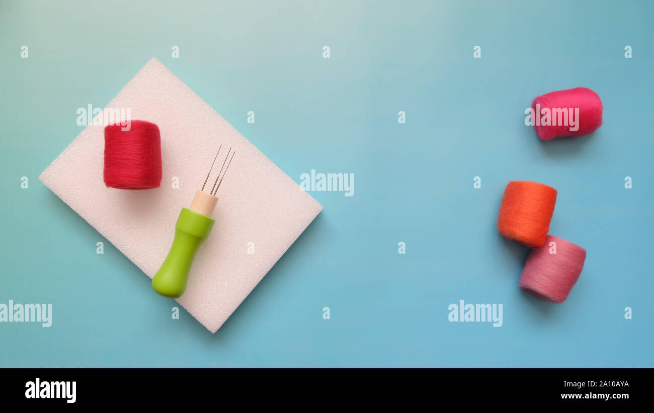 Piatto di laici rosso, arancione e rosa Lana Feltro rotoli e kit di infeltrimento di feltro ago e spugna. Foto Stock
