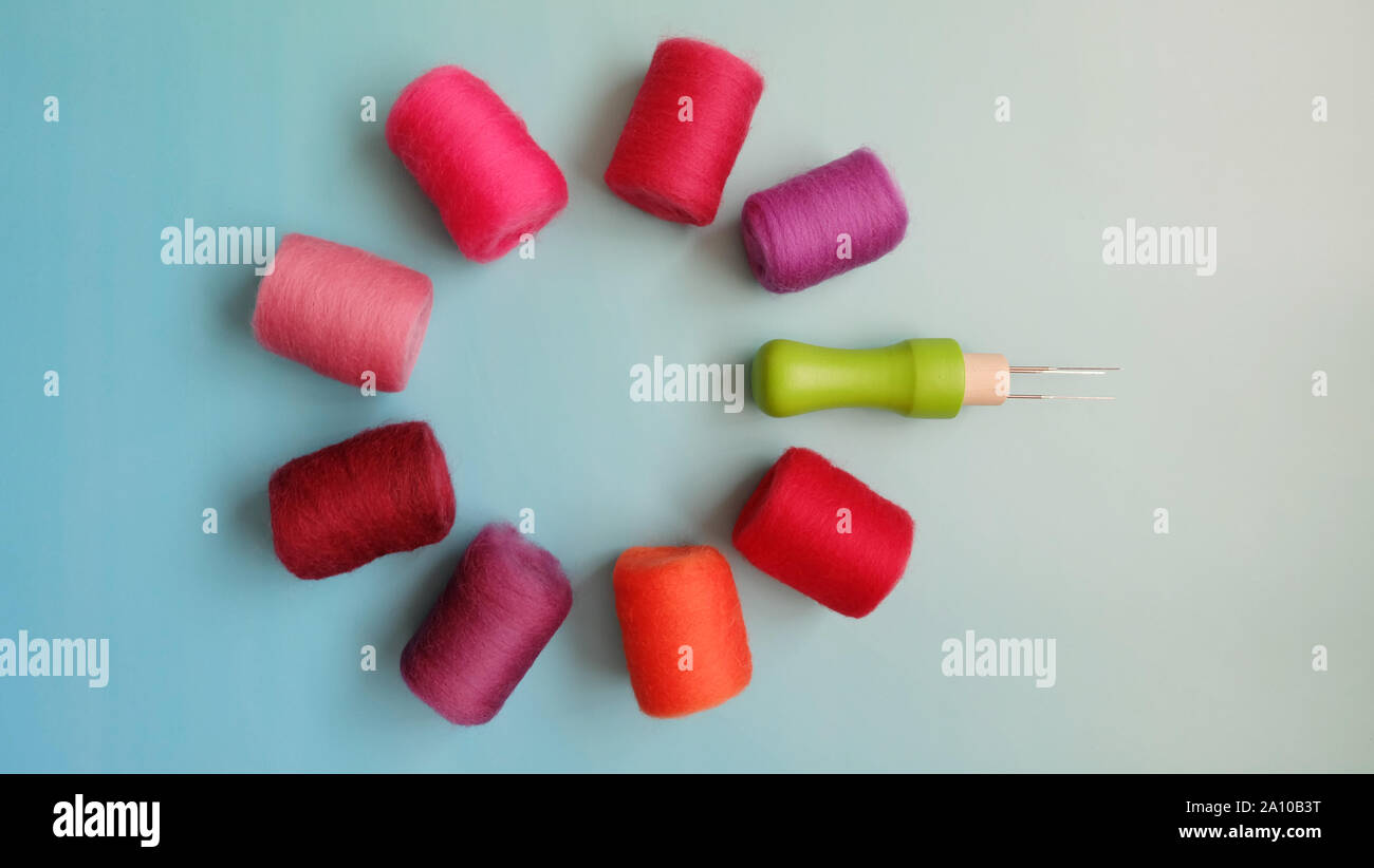 Laici piana del rosso e del rosa Lana Feltro rotoli e ago feltro disposti in un cerchio. Foto Stock