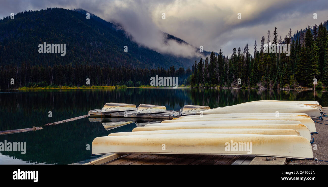 Canoe resto sul dock dal lago su un inizio di mattina nuvoloso Foto Stock