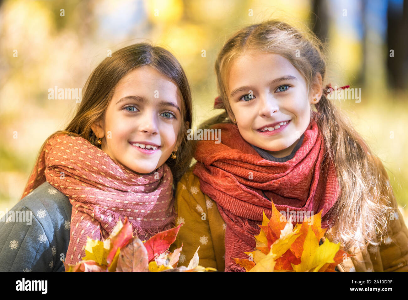 Due graziosi sorridente 8 anni le ragazze in posa insieme in un parco su una soleggiata giornata autunnale. Foto Stock