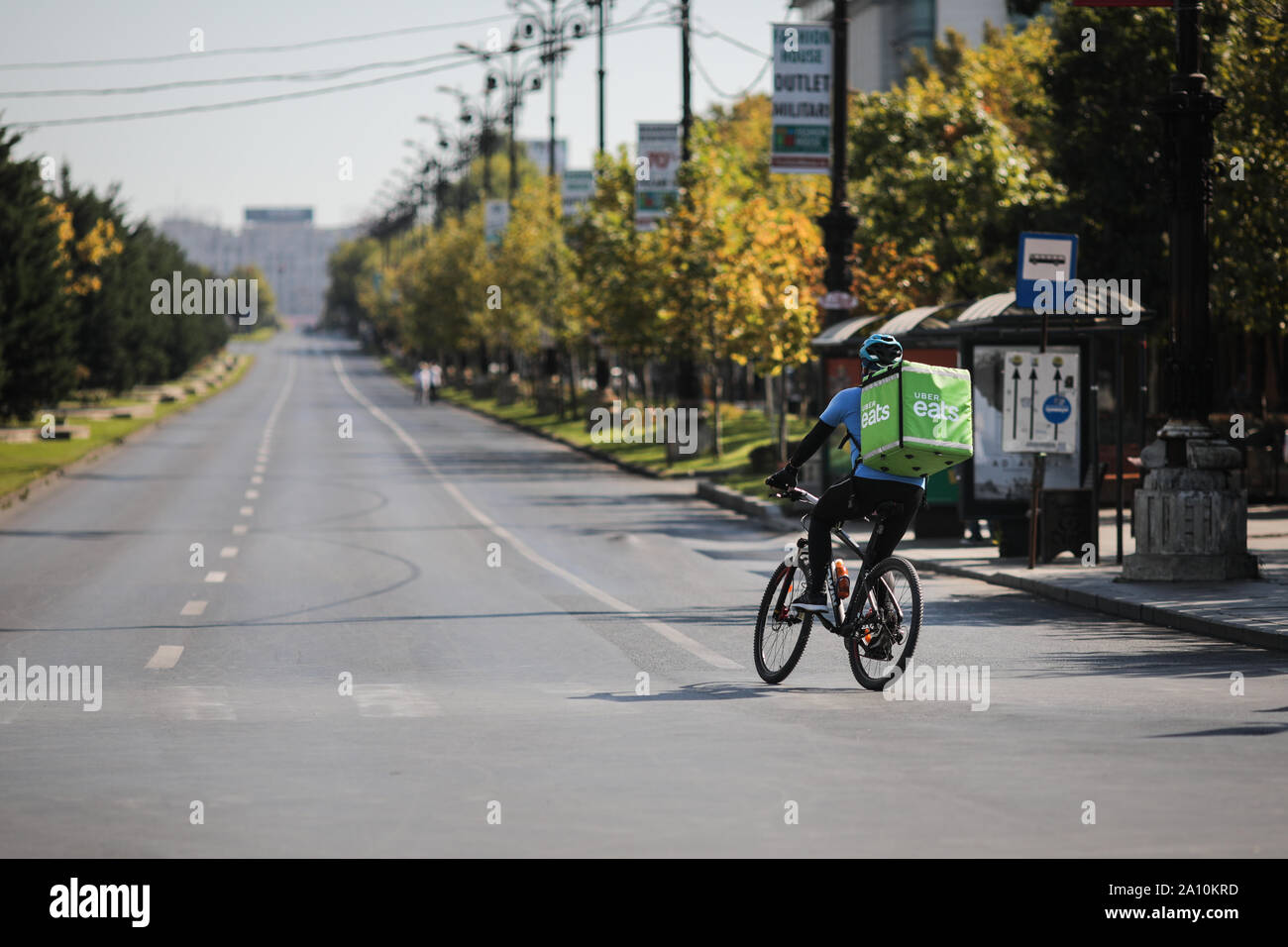 Bucarest, Romania - 22 Settembre 2019: UBER Mangia la consegna biker su un vuoto di boulevard durante una giornata di sole. Foto Stock