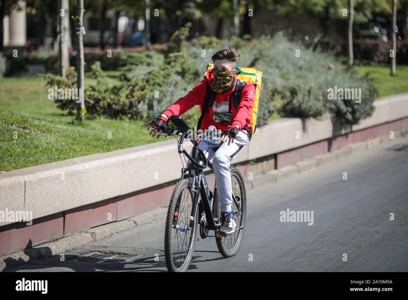 Bucarest, Romania - 22 Settembre 2019: consegna Glovo biker su un vuoto di boulevard durante una giornata di sole. Foto Stock