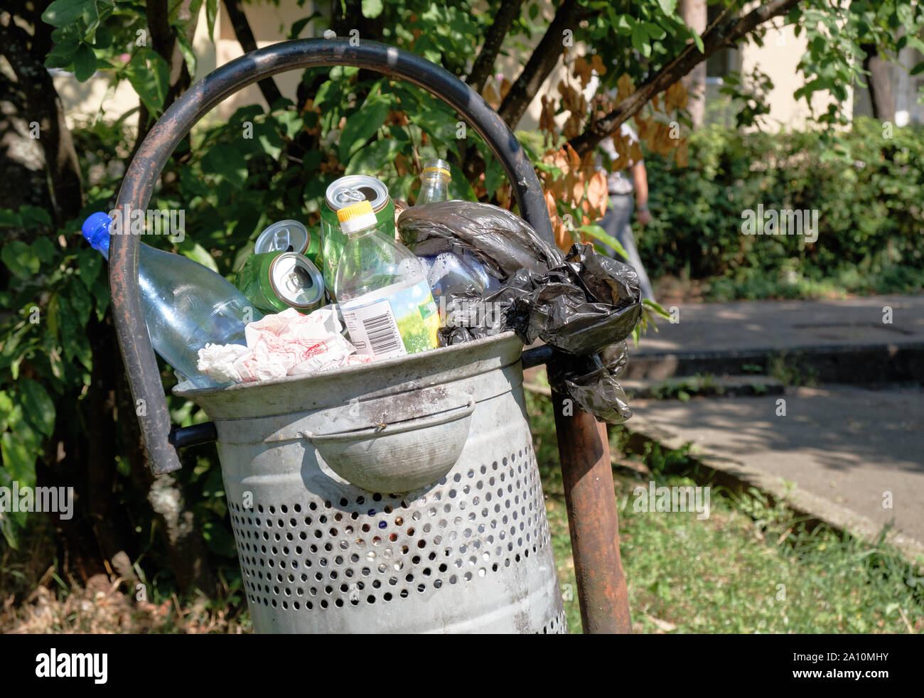 Parco di metallo spazzatura traboccante di vuoto di lattine di birra e bottiglie di plastica Foto Stock